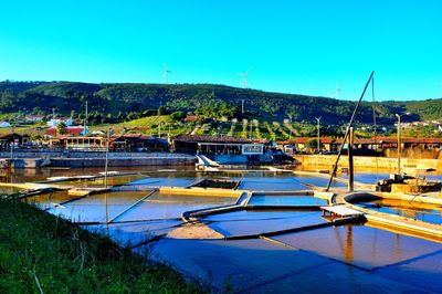 Boats moored at harbor against clear blue sky