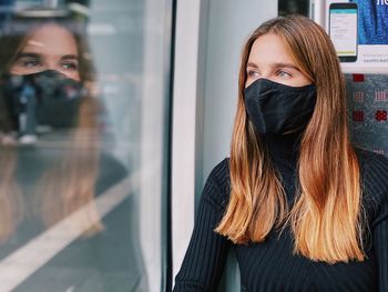 Woman wearing mask looking through glass window