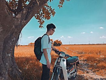 Young man riding bicycle on field against sky