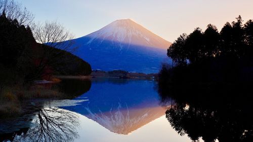 Scenic view of lake by mountains against sky during winter