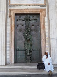 Statue of man sitting outside building