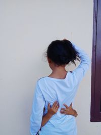 Person embracing girl while standing against white wall