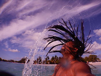 Man splashing water against sky