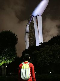 Rear view of man looking at camera against sky at night