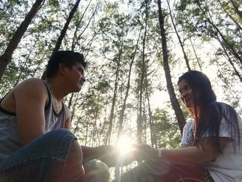 Young couple sitting on land in forest