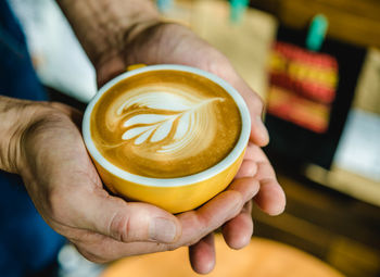 Cropped hands holding coffee in cup at cafe