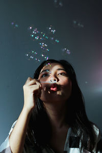 Portrait of a beautiful young woman looking at bubbles