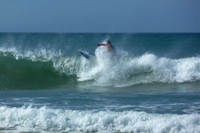 Person surfing on sea against sky