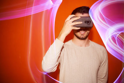 Young man taking a photo in a colored light background