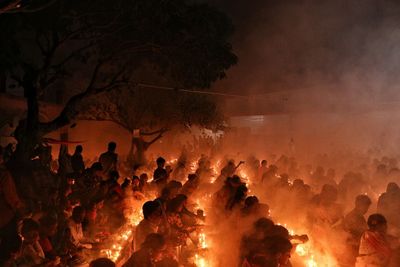 People are praying at rakher upobash under big tree in a smokey environment