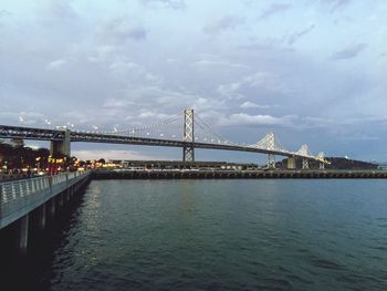 Bridge over river against cloudy sky