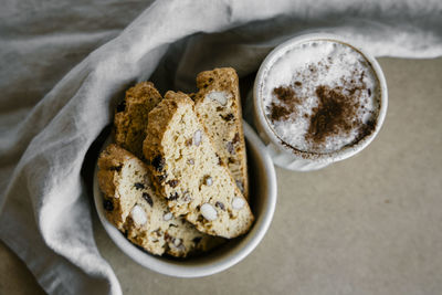 Freshly baked almond biscottis with cup of cappuccino on wooden background. 