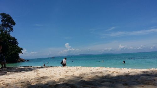 People on beach against blue sky