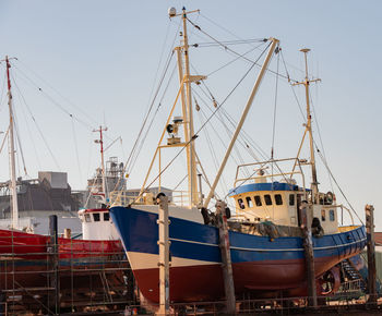 Sailboats moored at harbor against clear sky