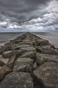 Rocks on shore by sea against sky