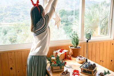 Female florist blogger making winter ikebana with pine branches, candle and christmas decorations