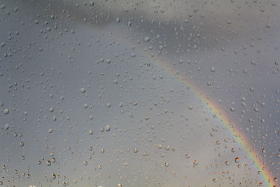 Window with raindrops with rainbow on the background