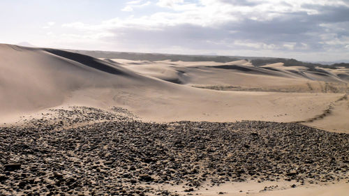 Scenic view of sand dunes against sky