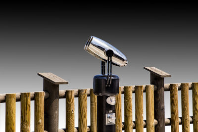 Coin-operated binoculars by railing against sky