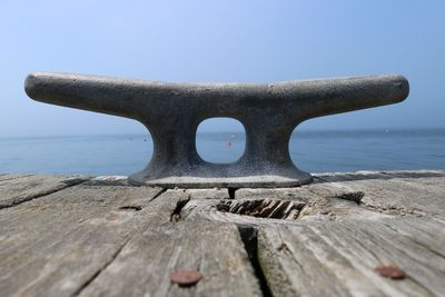 Close-up of rusty chain on wood against sky