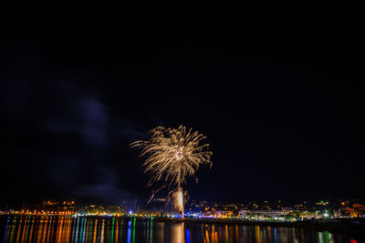 Firework display over illuminated buildings in city at night