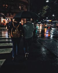 Rear view of people walking on wet road