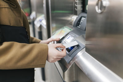 Woman using credit card on ticket machine at station