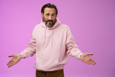 Portrait of man standing against pink background