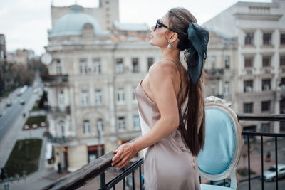 Young woman standing by railing in city