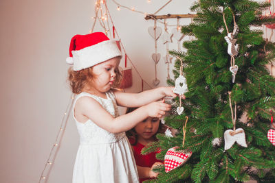 Cute girl decorating christmas tree at home