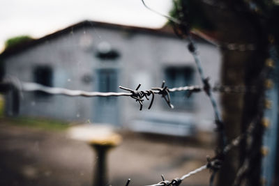 Close-up of barbed wire fence against building