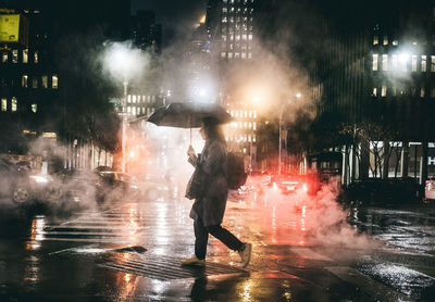 People on wet street in city at night