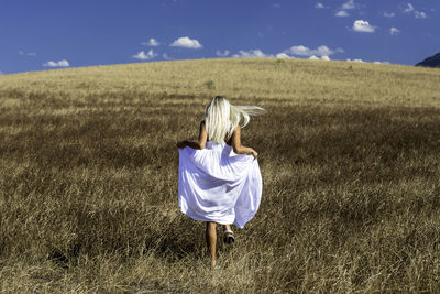 Rear view of woman walking on field