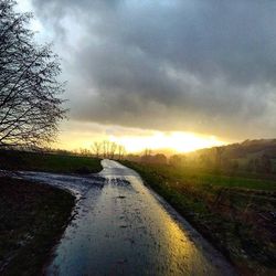 Scenic view of road against cloudy sky at sunset