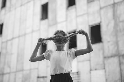 Woman holding umbrella standing against wall