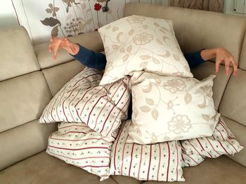 Woman hiding behind cushion on sofa