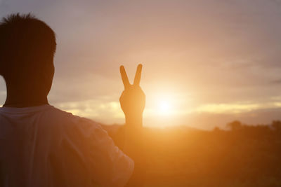 Rear view of silhouette person against sky during sunset