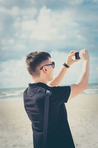 Man photographing sea against sky