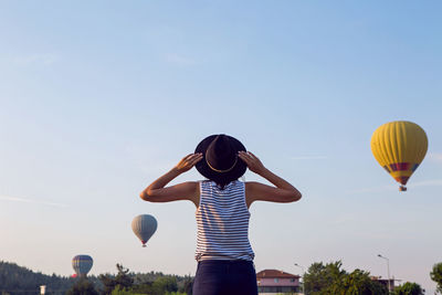 Woman in a striped t-shirt and hat stands in pamukkale and looks