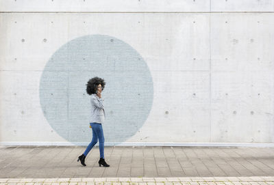 Side view of woman standing against wall