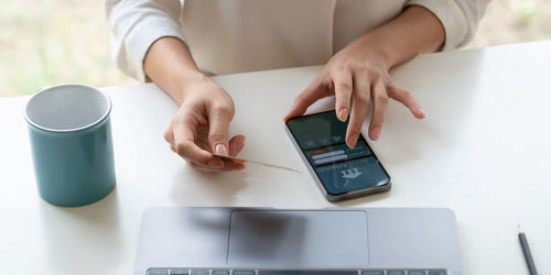 Midsection of woman using smart phone on table