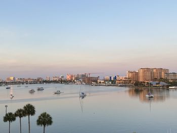 Scenic view of river by buildings against sky during sunset