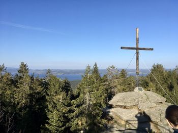 Cross amidst trees against blue sky