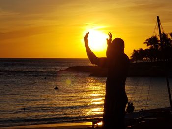 Silhouette man standing on beach during sunset