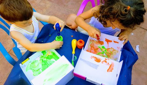 High angle view of siblings on painting on boxes