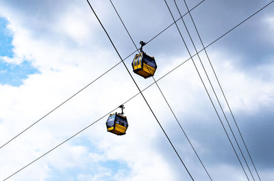 Low angle view of overhead cable cars against sky