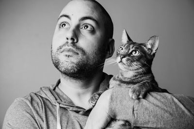 Portrait of young man with cat against gray background