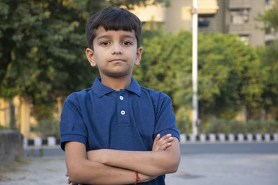 Portrait of boy standing with arms crossed outdoors