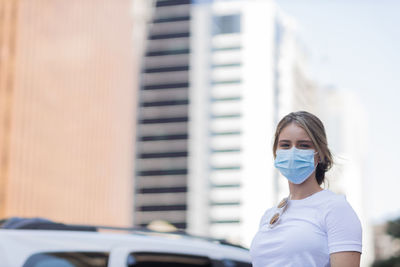 Woman wearing a medical protective mask on his face on city street 