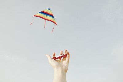 Cropped image of woman flying kite against clear sky